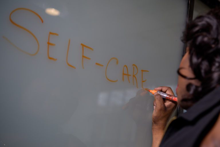 Sandy Linda writing self-care on a white board.